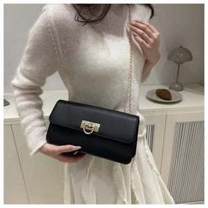 Détail du sac à bandoulière en cuir noir avec boucle dorée en U et bandoulière chaîne