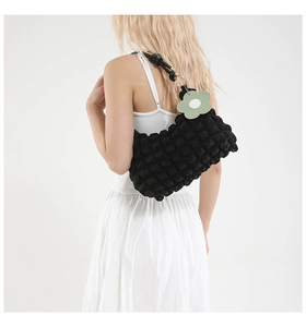 Detail of black popcorn texture shoulder bag with light green flower charm accessory