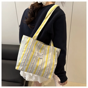 Detail of the striped canvas tote bag showing yellow, blue and white vertical patterns