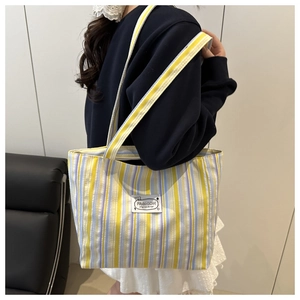 Detail of colorful striped canvas tote bag showing the fashion label and fabric texture