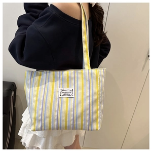 Detail of colorful striped canvas tote bag showing the fabric texture and shoulder strap