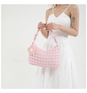 Detail of pink bubble texture shoulder bag with a floral charm and knotted strap handle