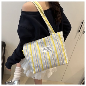 Detail of blue and yellow striped canvas tote bag with fashion original design patch