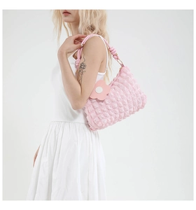Detailed shot of pink bubble textured shoulder bag with floral charm and knotted strap