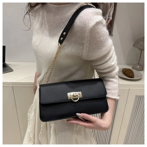 Détail du sac bandoulière vintage en cuir noir avec boucle dorée et bandoulière chaîne