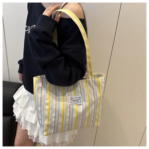 Detailed shot of striped canvas tote bag with yellow and blue vertical pattern and logo