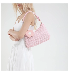 Close-up of pink quilted crossbody bag with knotted shoulder strap and flower charm