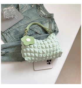 Detail of mint green cloud bag with textured bubble fabric and floral pendant