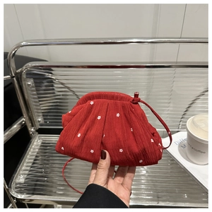 Détail du sac plissé rouge en forme de nuage avec fleurs blanches et bandoulière