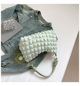 Detail of mint green bubble texture bag with floral charm on white minimalist background