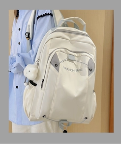 Detail of off-white nylon backpack with gray zipper, featuring a cute sheep plush charm