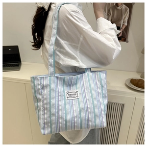 Close-up of blue striped canvas tote bag with a white fashion patch on the front