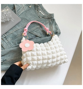 Detailed shot of white ruched handbag with pink knotted handle and flower charm detail