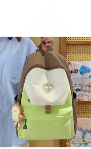 Detail of color-block backpack with creative plush bread pendant and round fashion patch