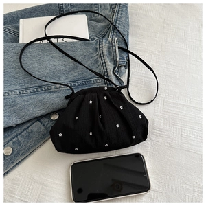 Gros plan d'un mini sac floral noir sur une veste en jean et une nappe à carreaux blanc