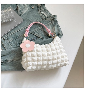 Detailed close-up of white bubble texture bag with pink woven handles and flower charm