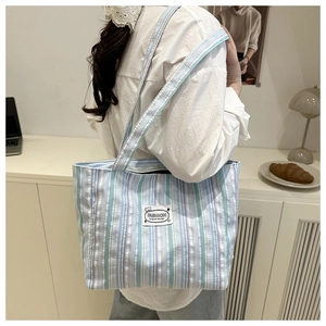 Close-up of striped canvas tote bag showing the fashion label and soft cotton texture