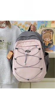 Détail d'un sac à dos scolaire rose et gris avec cordons croisés et charm décoratif