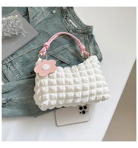 Close-up of white bubble texture shoulder bag with pink woven handle and flower charm