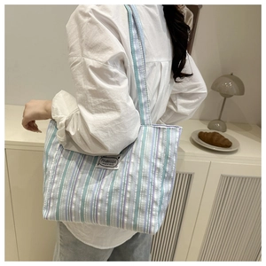Lifestyle shot of large striped canvas tote bag in pastel blue and purple tones