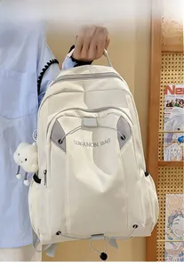 Detail of a large creamy white nylon backpack featuring a cloud pendant and elastic cords