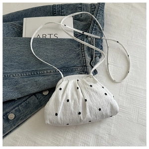 Détail d'un sac cabas plissé blanc avec de délicates broderies de fleurs noires