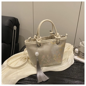 Detail of embroidered floral patterns on beige brocade bag with a long tassel charm