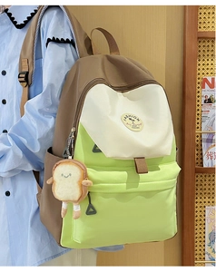 Detailed shot of tricolor nylon backpack with side pocket and toast plush charm
