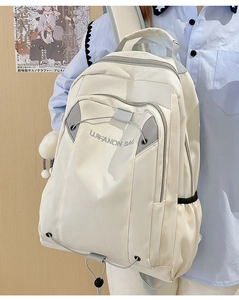 Detail of off-white waterproof nylon backpack featuring plush ball pendant and embroidery