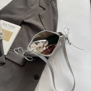 Silberne Halbmond-Tasche mit Schleifen-Details auf einem grauen Blazer-Outfit