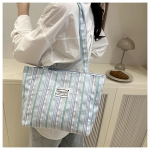 Close-up of mint green and purple striped canvas tote bag with fashion woven label