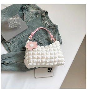 Close-up of white bubble texture fabric bag with pink knotted strap and flower charm