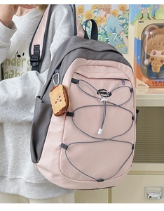 Détail du sac à dos rose et gris avec cordons élastiques et breloque en peluche