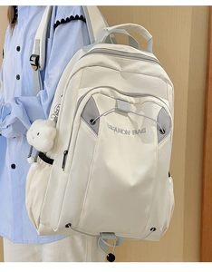 Detail of cream white waterproof backpack featuring a cloud pendant and side pocket