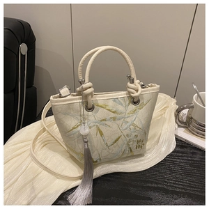 Detail of beige jacquard bucket bag with leaf embroidery and elegant silver tassel
