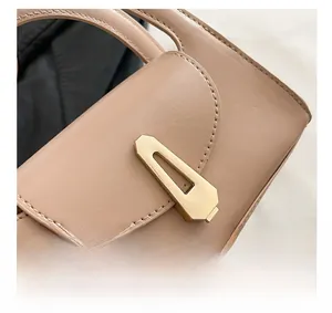 Nahaufnahme der goldenen Metallschnalle und Nähte an der beigen Lederhandtasche