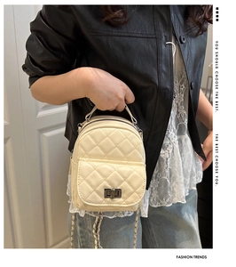 Detail der cremeweißen gesteppten Mini-Tasche mit silbernem Drehverschluss und Kette