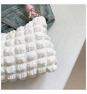 Close-up of white bubble texture fabric with pink knotted leather handle and metal rings