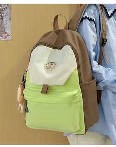 Detailed view of tricolor patchwork backpack with plush pendant and side pocket