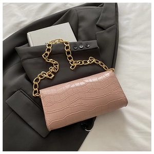 Dettaglio borsa rosa con motivo a pietra e grossa catena dorata su un blazer