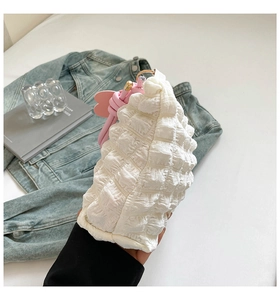 Close-up of white ruched fabric texture with a pink knotted decorative strap detail