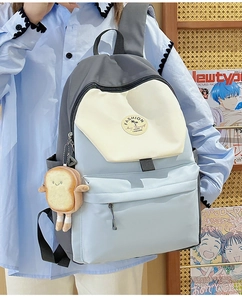Detail of color-block nylon backpack featuring a toast plush charm and fashion patch