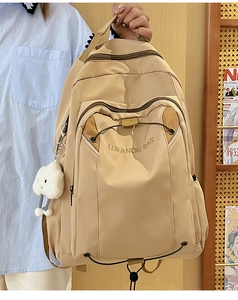 Detail of a beige large-capacity backpack featuring elastic drawstrings and a plush cloud charm
