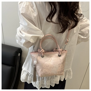 Detailed view of pink silk bucket bag with traditional Chinese embroidery and tassel