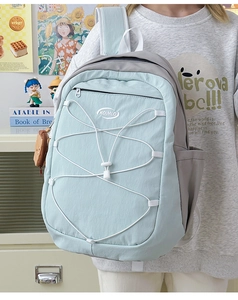 Détail du sac à dos bleu clair et gris avec système de cordon élastique blanc fonctionnel