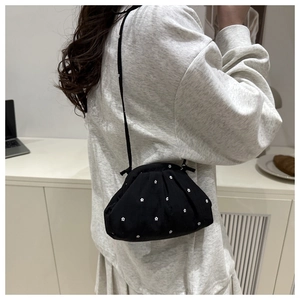 Détail du sac nuage plissé noir à fleurs porté en bandoulière pour un style décontracté