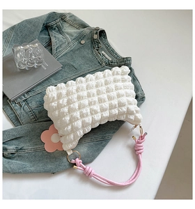 Detail of white bubble texture handbag with pink knot handle and floral charm accessory
