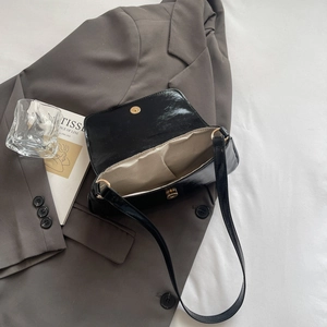 Sac sous le bras noir brillant chic avec fermoir magnétique doré sur fond stylisé