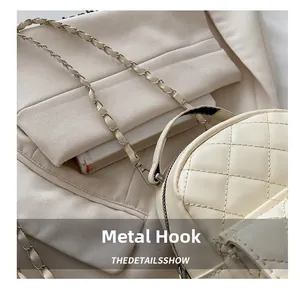 Close-up of the metal hook detail and gold chain strap on the beige quilted backpack