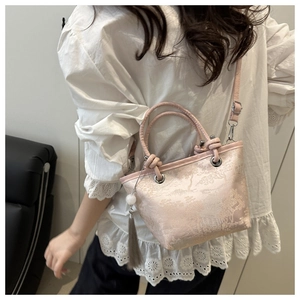 Close-up of pink jacquard bucket bag with oriental embroidery and tassel detail